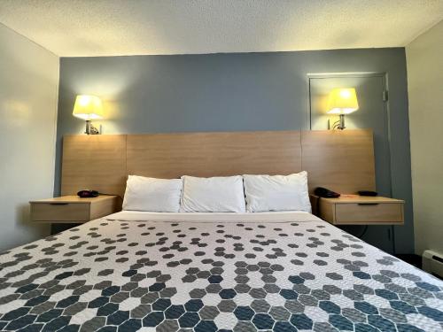 a bed in a hotel room with two lamps on the wall at Econo Lodge Motel Village in Calgary