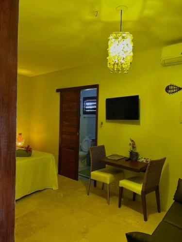 a yellow living room with a table and a television at The Wind Village in Itarema
