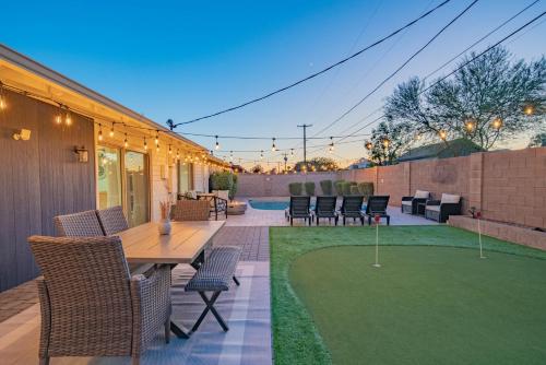 un patio con mesa, sillas y césped verde en Spacious 4BD with Pool and Putting Green Near Old Town Scottsdale, en Scottsdale
