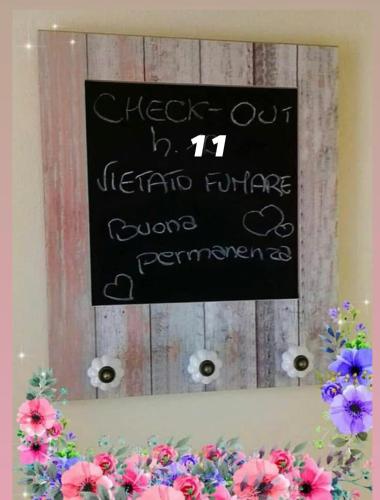 a chalkboard sign on top of a table with flowers at DIMORA MELISSA in Colà di Lazise