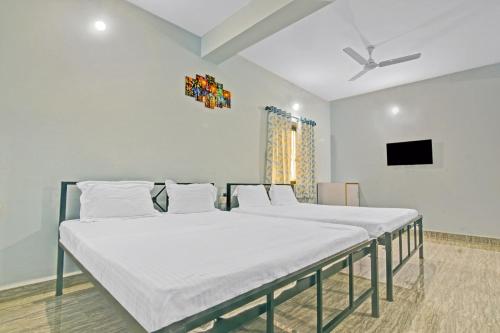 two beds in a room with a tv on the wall at Hotel O Sai Leela in Goa