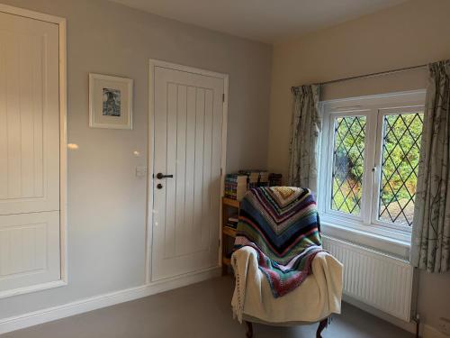 une pièce avec une chaise avec une couverture dessus dans l'établissement Chineway Cottage, à Ottery St Mary