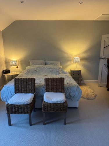 a bedroom with a large bed with two chairs at Chineway Cottage in Ottery Saint Mary