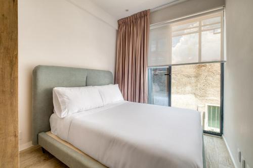 a bedroom with a white bed and a window at Myla Chapultepec in Mexico City