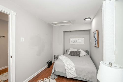 a white bedroom with a bed and a lamp at The Covington Cottage Modern 2 BDR Charmer in Covington