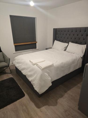 a bedroom with a large bed with white sheets and a window at Comphy homes in Rainham