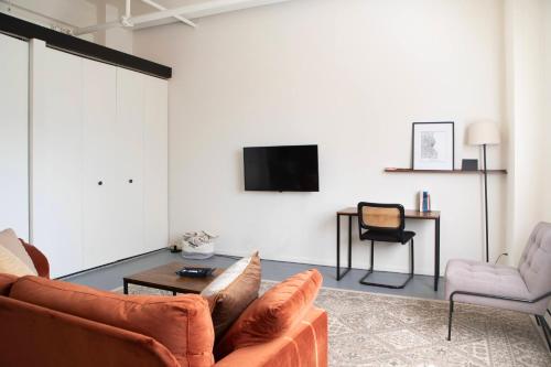 sala de estar con sofá, TV y silla en Westown Studio Apt Near Fiserv, Baird, and Theater District, en Milwaukee