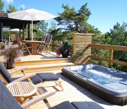 a deck with a hot tub and a table and chairs at 5-star homestay for 2 with breakfast, hot-tub, aircon and bikes in Ingarö