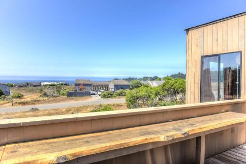 a wooden bench sitting on the balcony of a house at Sea Meadow - Panoramic Ocean View in Sea Ranch