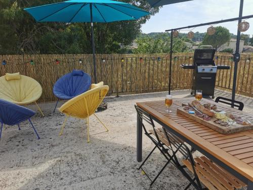 - une table de pique-nique et des chaises avec un grill et un parasol dans l'établissement 50m2, 4 personnes , jacuzzi et sauna privatif, à Piolenc
