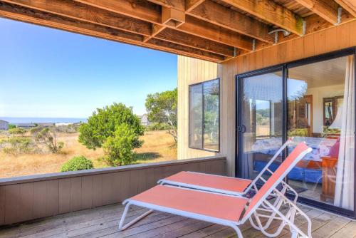a rocking chair on a porch with a large window at Sea Meadow - Panoramic Ocean View in Sea Ranch