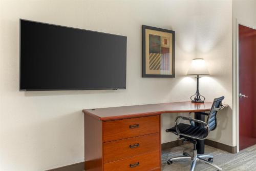 a desk with a television on a wall with a chair at Best Western Plus Waxahachie Inn & Suites in Waxahachie