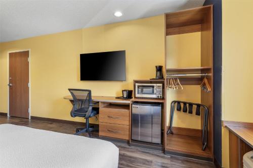 a hotel room with a desk with a computer and a microwave at SureStay Plus Hotel by Best Western Keyser in Keyser