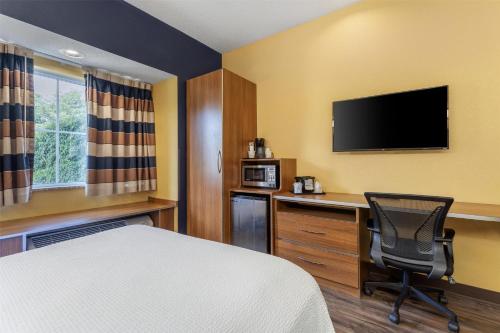a hotel room with a bed and a desk and a television at SureStay Plus Hotel by Best Western Keyser in Keyser