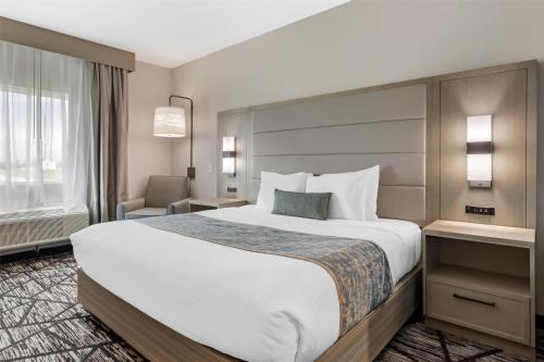 a hotel room with a large bed and a chair at Best Western Plus Mid County in Port Arthur