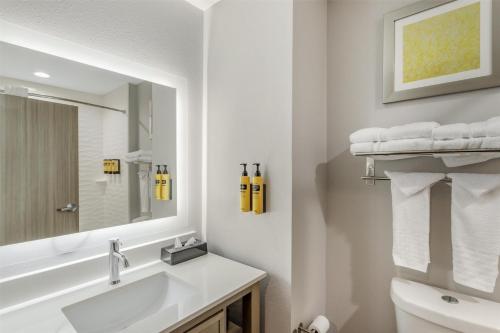 a white bathroom with a sink and a mirror at Best Western Plus Mid County in Port Arthur