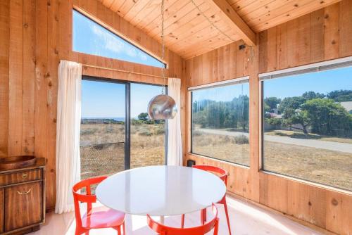 a dining room with a table and chairs and windows at Incredible Sea Ranch Escape for 6 With Ocean Trail in Sea Ranch