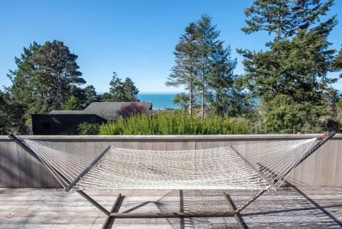a hammock on a patio with the ocean in the background at Charming 3 BD Family Home for 6 with Ocean Views & Trail Access in Sea Ranch