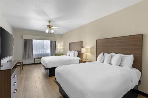 a hotel room with two beds and a flat screen tv at Best Western Firestone Inn & Suites in Longmont