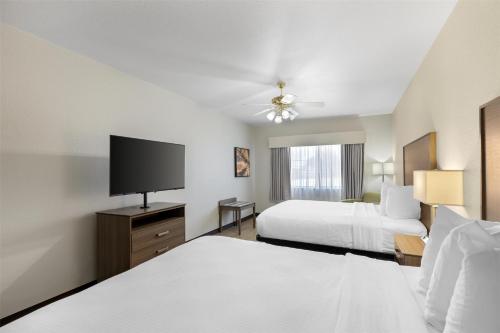 a hotel room with two beds and a flat screen tv at Best Western Firestone Inn & Suites in Longmont