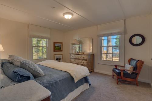 a bedroom with a bed and a chair and windows at Belleview Lakefront by Tahoe Getaways - Hot Tub, Pier, Buoy and Guest House in Homewood