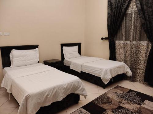 a room with two beds with white sheets and a window at فخامة المصيف للشقق المخدومة 2 in Taif