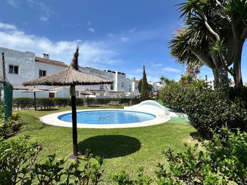 una piscina con sombrilla en un patio en Barrosa Living, en Chiclana de la Frontera