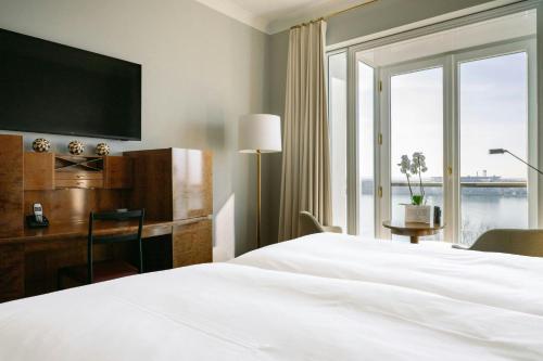a hotel room with a bed and a desk and window at Louis C Jacob, Hamburg, Autograph Collection in Hamburg