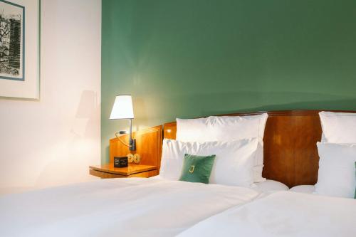 a bedroom with two beds with white sheets and a green pillow at Louis C Jacob, Hamburg, Autograph Collection in Hamburg