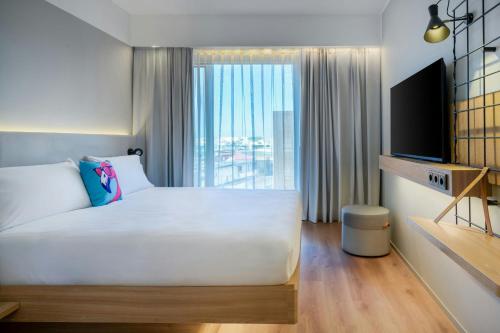 a bedroom with a large white bed and a tv at Moxy Verona in Verona