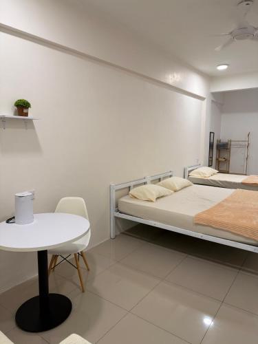 a white room with two beds and a table at Cozy Inn Homestay in Kampar