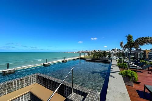 una piscina con la spiaggia sullo sfondo di Flat pé na areia Alta Garden - MyFlats Hospedagens a João Pessoa