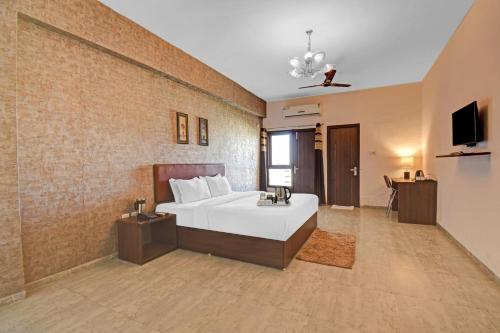 a bedroom with a white bed and a brick wall at Townhouse Classio Suites in Shirdi