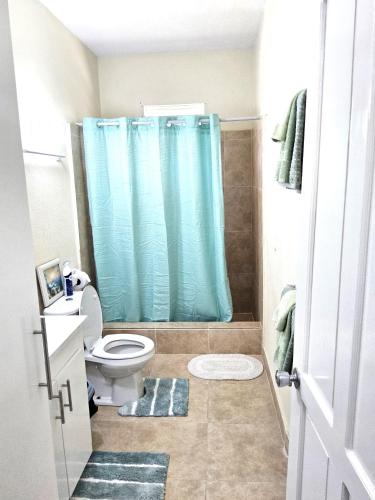 a bathroom with a toilet and a blue shower curtain at OB Apt 2 in Christ Church