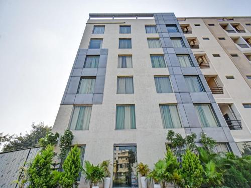 a tall building with trees in front of it at Townhouse Classio Suites in Shirdi