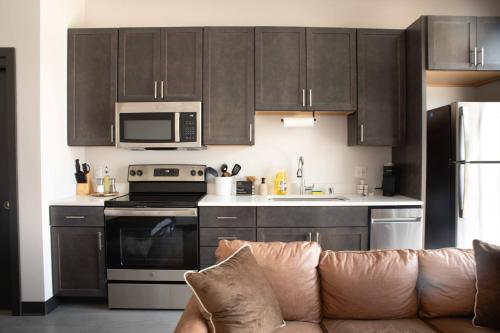 a kitchen with brown cabinets and a couch at Deer District Studio Apt - One Block from Fiserv & Baird in Milwaukee