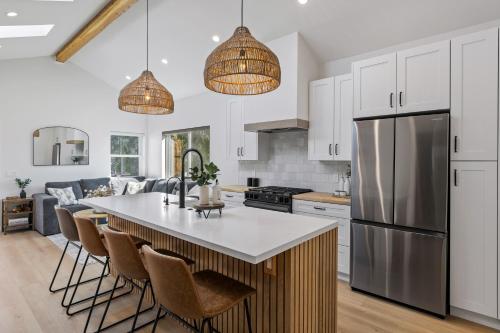 a kitchen with white cabinets and a kitchen island with bar chairs at The Oaks, Stylish Luxury Stay, Fire Pit & Patio in Thousand Oaks