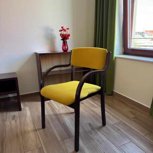a yellow chair with a desk and a vase of flowers at Vinařský dům V Zahradě in Pasohlávky