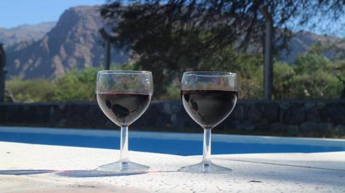 two glasses of wine sitting on a table near a pool at Cabañas Pukara in Cafayate