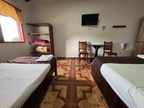 a room with two beds and a table and a tv at Hotel Balcon Tamesino in Támesis