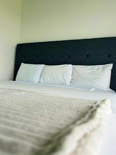 a bed with white pillows and a black headboard at Hotel Vista Al Mar in Capurganá