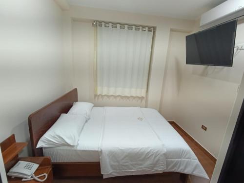 a bedroom with a white bed and a flat screen tv at Morro Calzada in Moyobamba