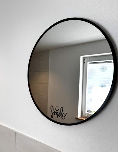 a round mirror on a wall with a window at Ferienwohnung Naturtraum in Mistelgau