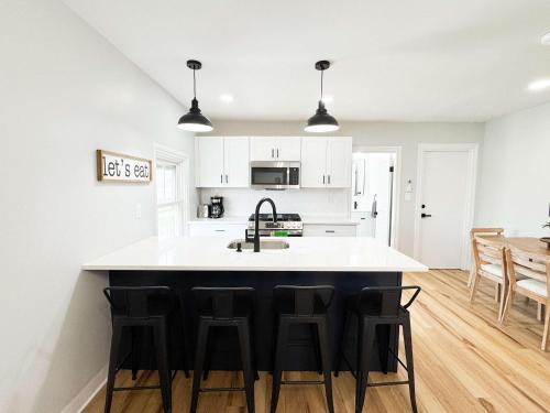 a kitchen with white cabinets and a black island with bar stools at Jennifer's Elegant & Cozy Broadway Walkable Stay in Providence