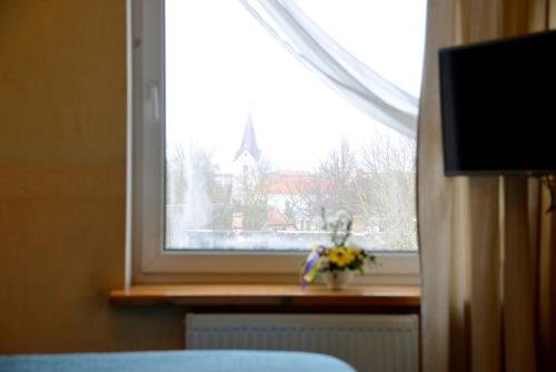 a window with a vase of flowers on a window sill at Demians in Saldus