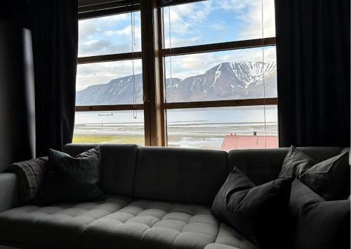 a couch in front of a window with a mountain view at Koselig rekkehus i Longyearbyen in Longyearbyen