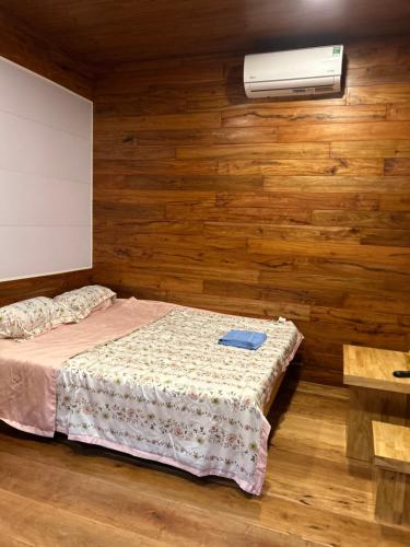a bedroom with a bed and a fan and wooden walls at Motel Tuệ Nhi II in Plei Kơtêng