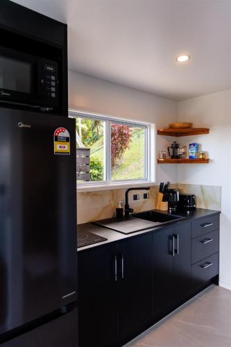 a kitchen with a black refrigerator and a window at Muri Ocean View Villas in Ngatangiia