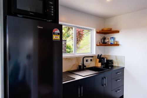 a kitchen with a black refrigerator and a sink at Muri Ocean View Villas in Ngatangiia
