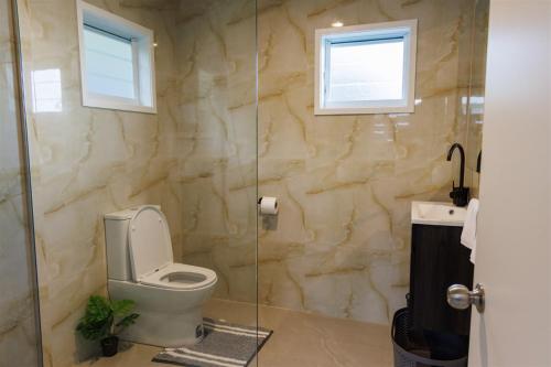 a bathroom with a toilet and a glass shower at Muri Ocean View Villas in Ngatangiia